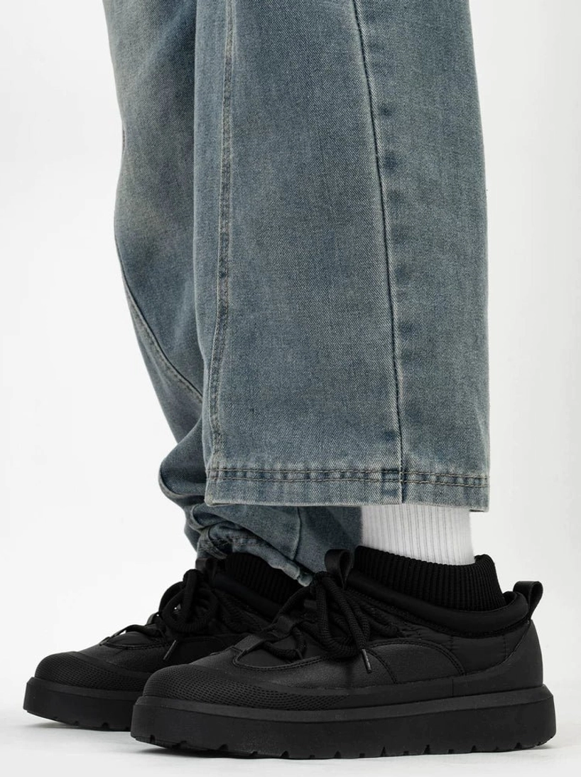 Black knit collar platform sneakers worn with baggy blue jeans and white socks, showing the chunky winter streetwear silhouette and ribbed ankle collar