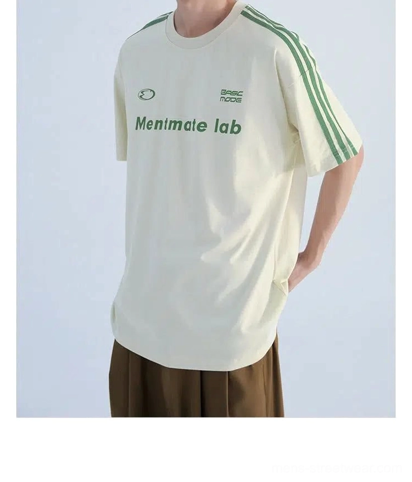 Black Korean casual streetwear T-shirt worn with a midi skirt and sneakers, featuring green shoulder stripes and a front chest graphic