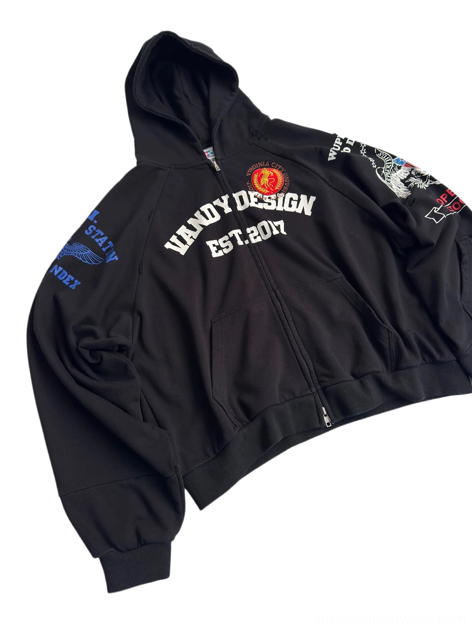 Oblique front view of black Korean streetwear zip hoodie showing oversized cropped fit, metal zipper, varsity chest graphic, and detailed sleeve embroidery