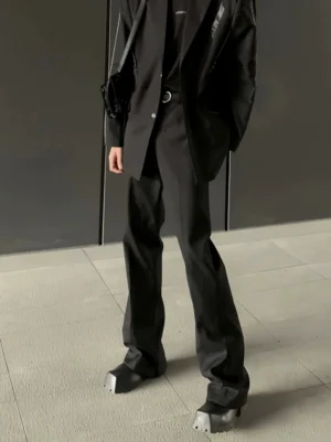 Black Korean streetwear flared suit trousers shown in a low angle full body front view with an elongated draped silhouette