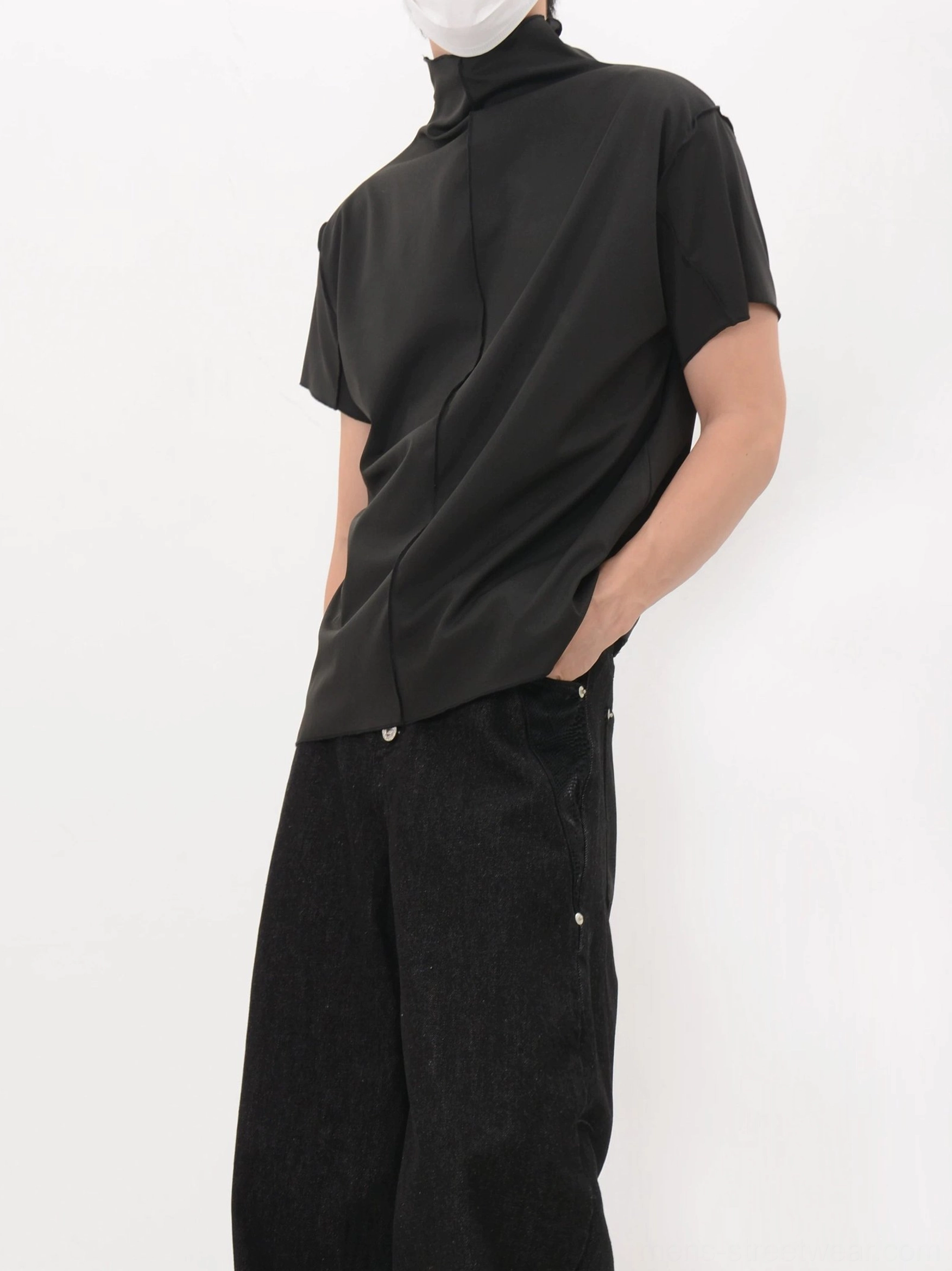 Side rear view of a black Korean streetwear mock neck shirt showing the loose fit, back seam, and curved hem
