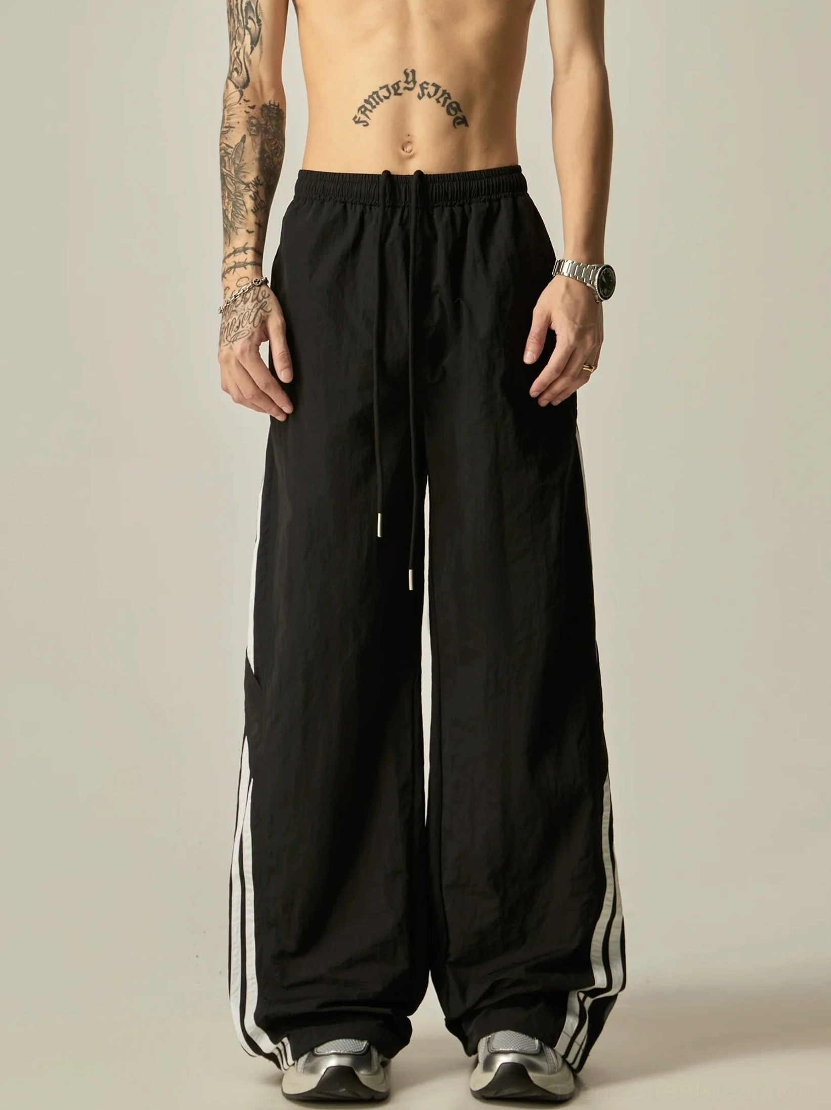 Full front view of black Korean streetwear wide-leg track pants featuring white side trim, adjustable drawstring waist, and full-length relaxed silhouette