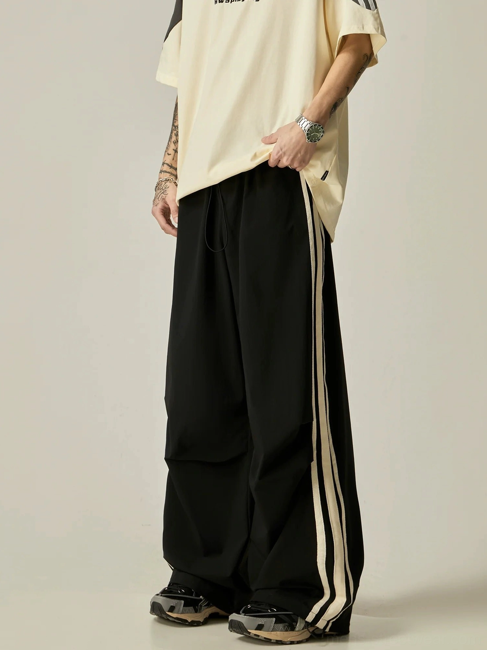 Black Korean streetwear wide-leg triple stripe athletic pants styled with an oversized beige t-shirt and retro sneakers