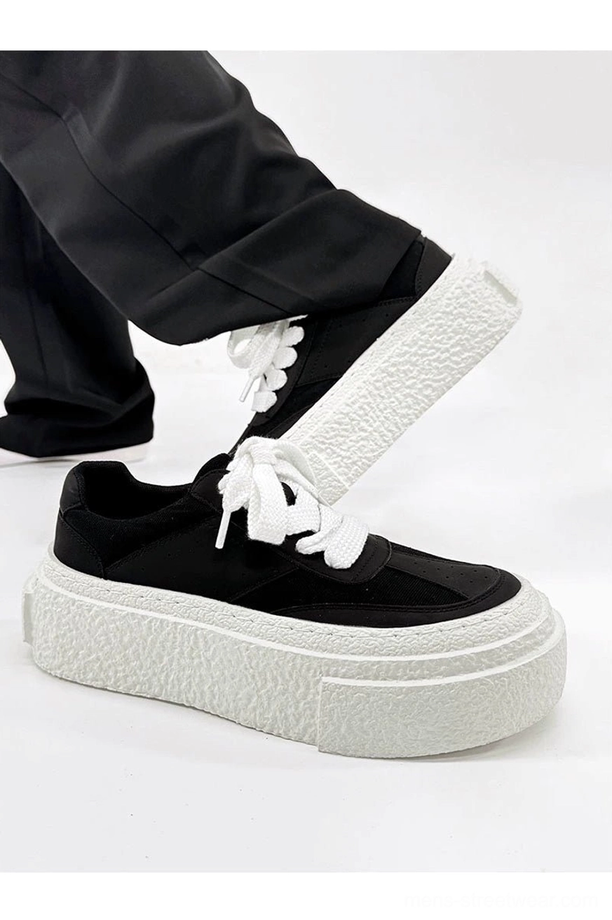 Low side view of black lace-up chunky sneakers with layered white textured platform soles