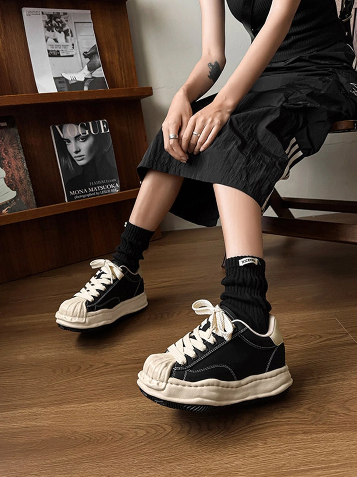 Side close-up of black lace-up distressed platform sneakers styled with a minimalist black dress