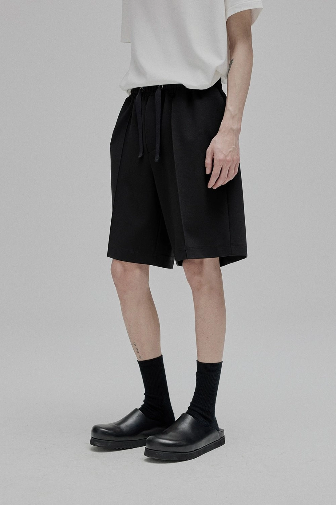 Male model wearing black lace-up straight leg full-length trousers studio streetwear minimalist aesthetic
