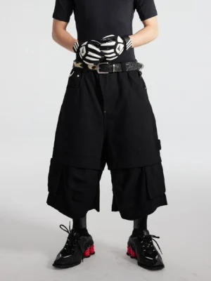 Black layered cargo culottes with wide cropped legs and stacked side utility pockets shown in a front three-quarter streetwear outfit