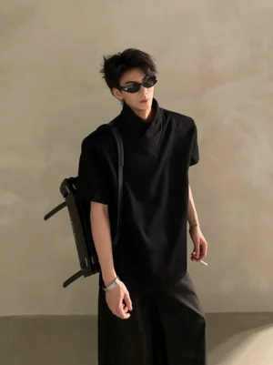 Black layered high-collar short-sleeve streetwear shirt on male model with sunglasses and shoulder bag in minimalist studio setting
