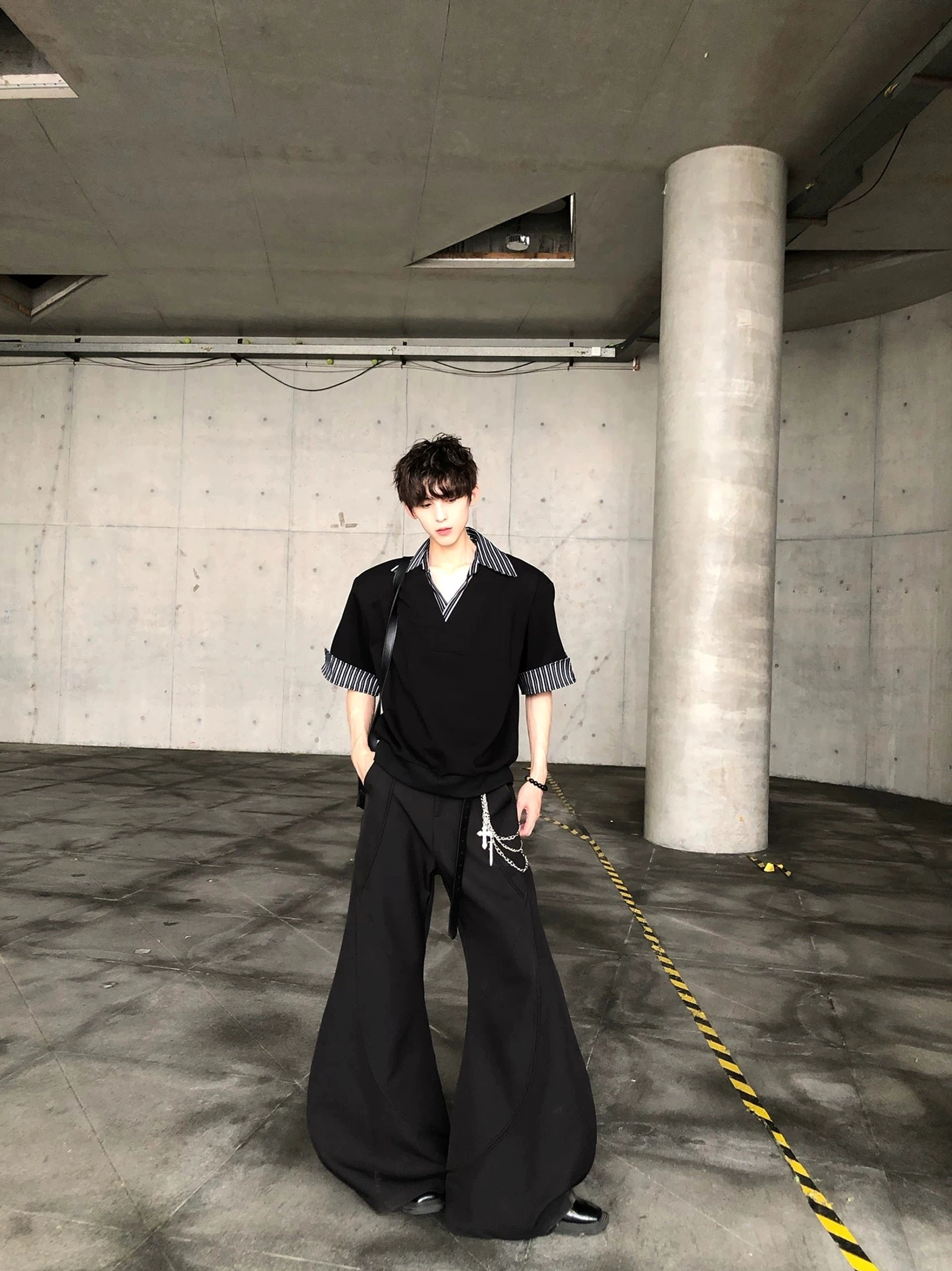 Back view of black oversized short sleeve streetwear shirt showing clean minimalist back and striped cuff accents