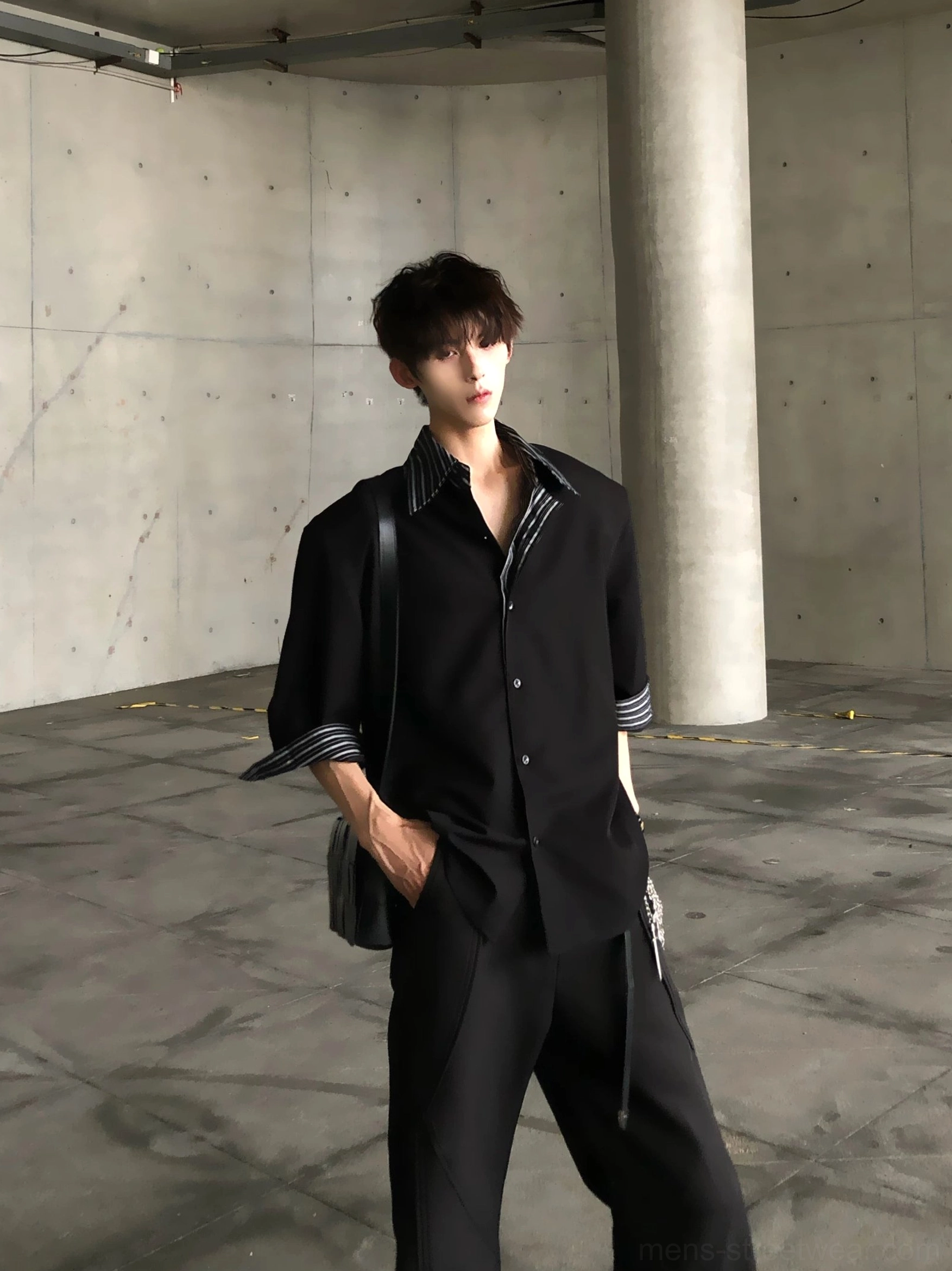 Side view of relaxed black layered stripe collar shirt with wide short sleeves and crossbody leather bag styling