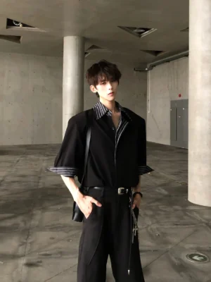 Front view of black layered stripe collar oversized streetwear shirt with grey white striped collar and rolled cuffs in an industrial setting