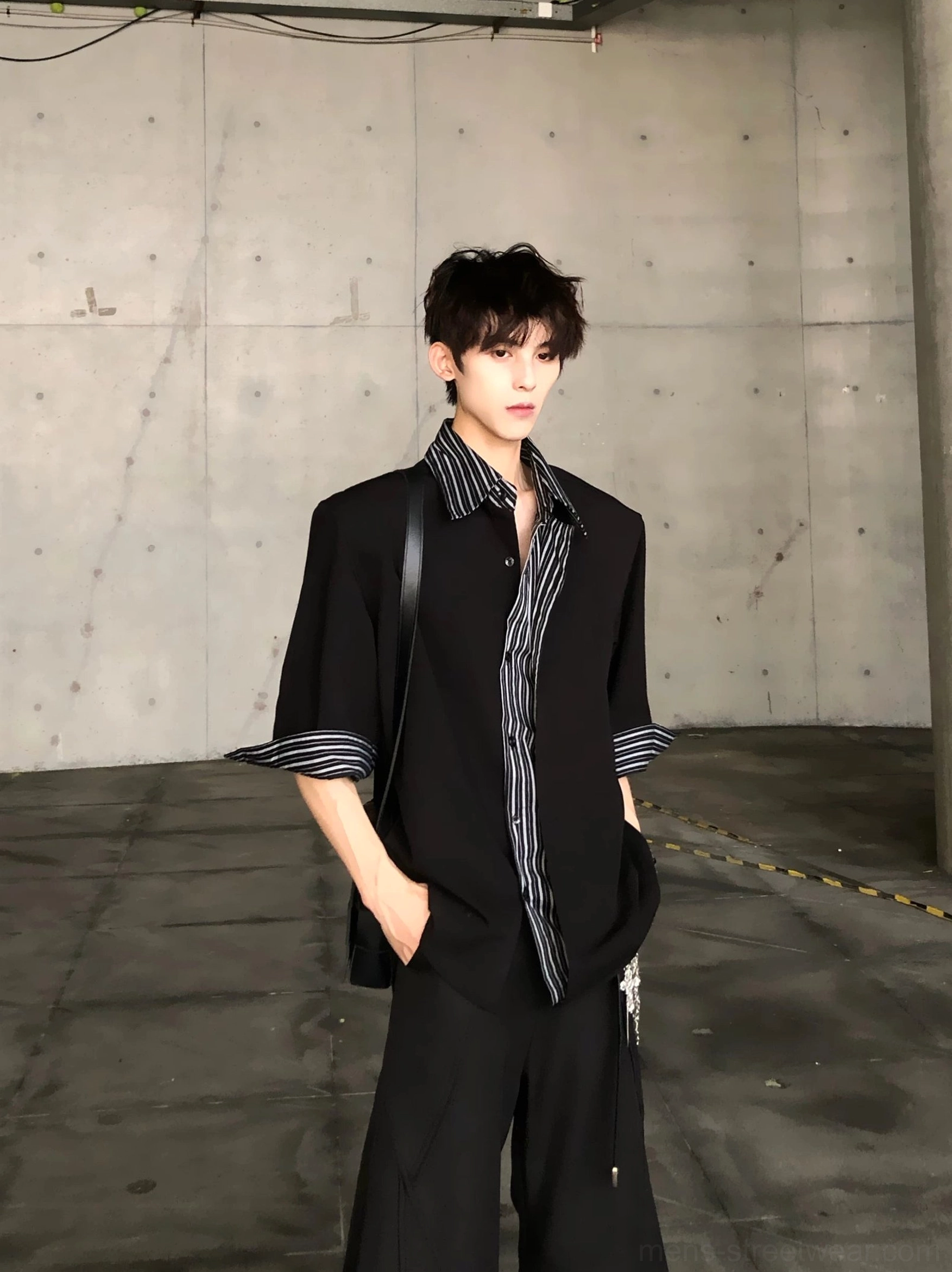Three quarter front view of black oversized stripe collar short sleeve shirt styled with crossbody bag and black trousers
