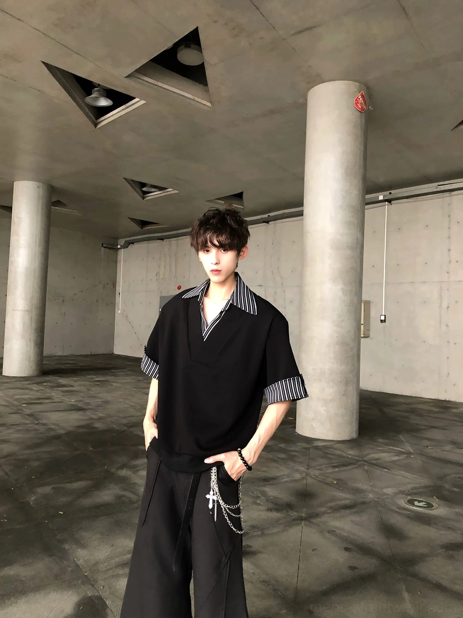 Front view of black V neck short sleeve streetwear shirt with grey white striped turn-up cuffs and wide leg pants