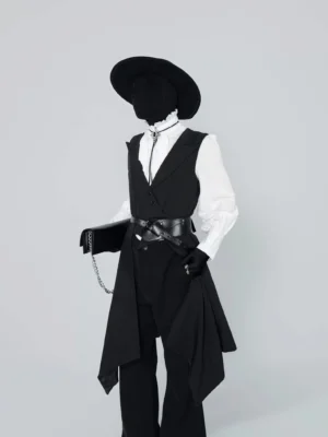 Three-quarter front view of black layered tailcoat vest with long draped panels and waist belt in an avant-garde gothic streetwear outfit