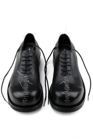 Pair of black leather Oxford shoes viewed from above showing black laces, polished cowhide uppers, and bold white center toe stitching
