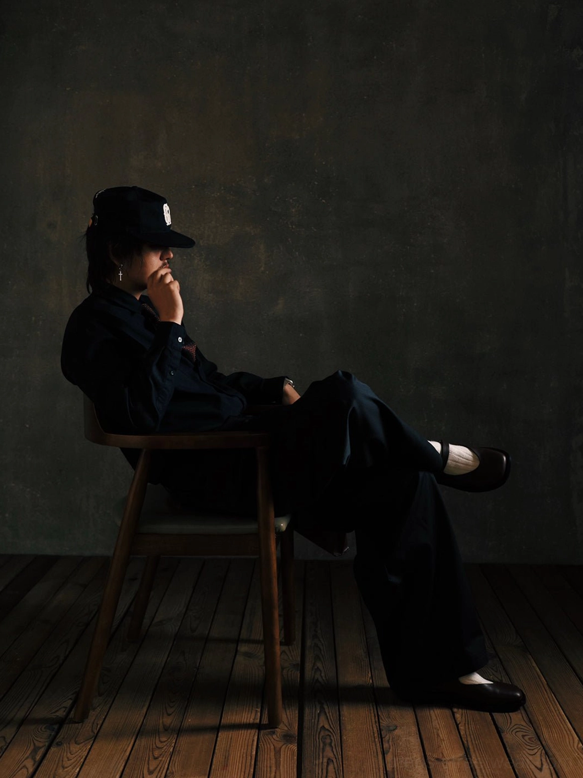 Black leather Mary Jane shoes worn with relaxed black workwear and a baseball cap for a modern Korean-inspired streetwear look