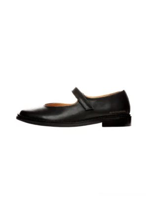 Side profile of black leather Mary Jane streetwear shoes showing the smooth upper, adjustable ankle strap, square toe, and low block heel on a white background