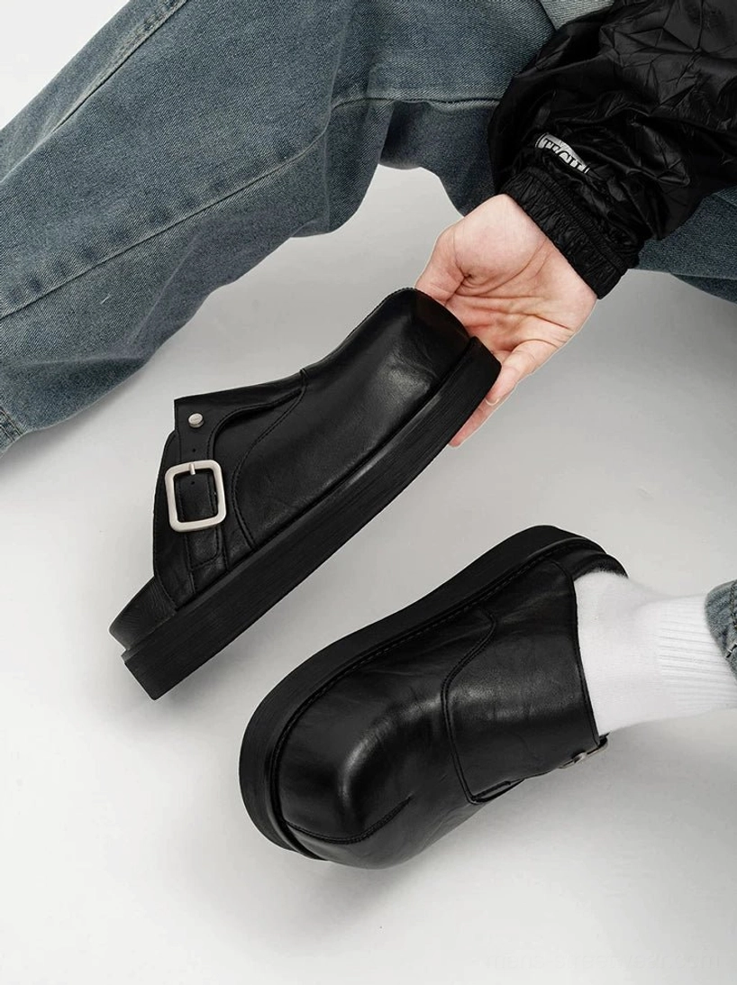 Overhead view of black leather platform buckle mule worn with a white crew sock showing soft leather texture and silver hardware