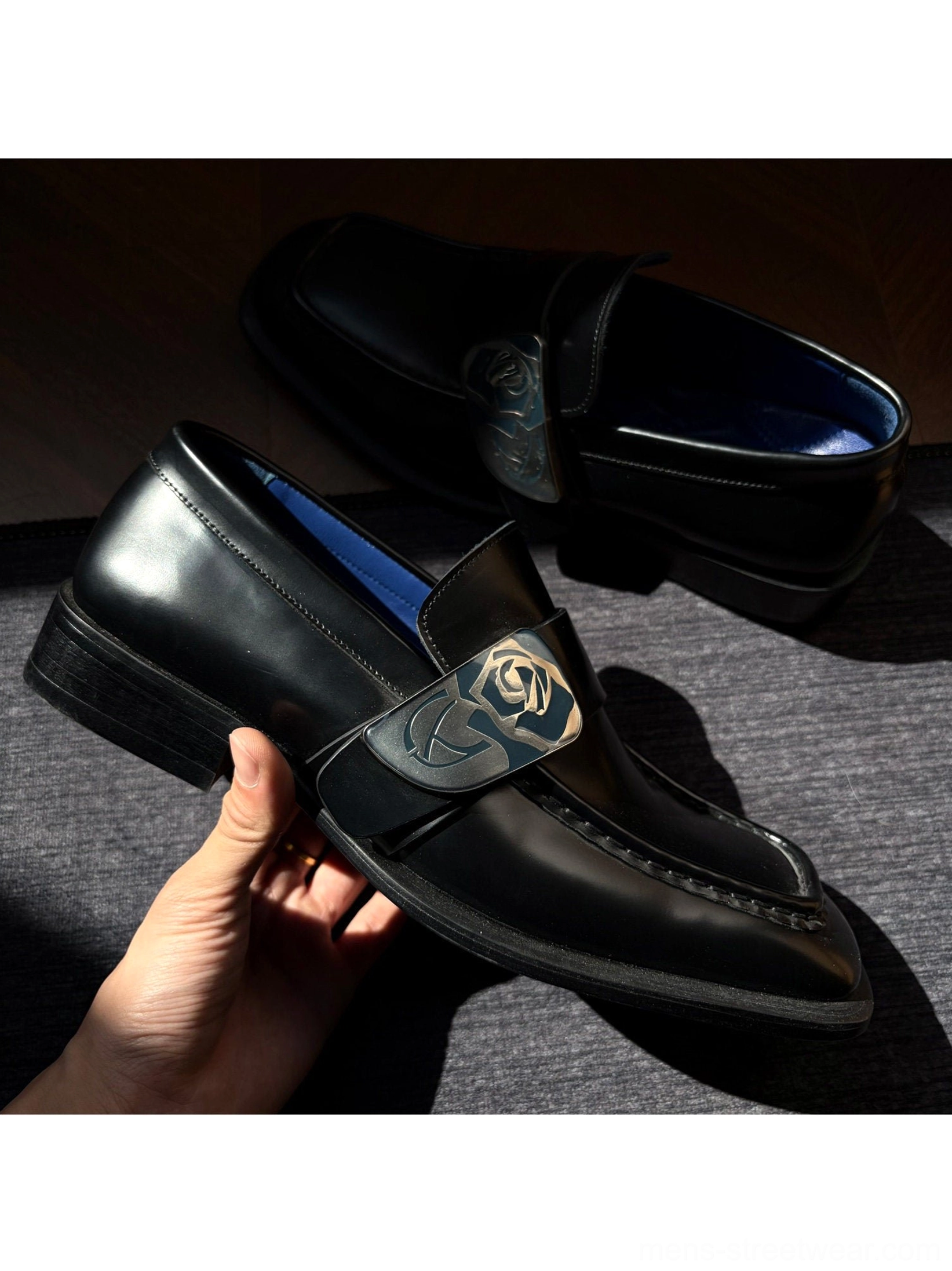 Close view of black leather rose crest loafers showing glossy upper decorative stitching and contrasting blue insole