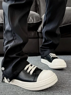 Black leather-textured chunky streetwear sneakers with white laces and thick rubber sole worn with black cargo pants