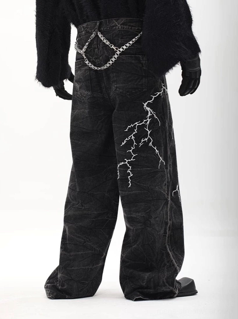 Rear three-quarter view of baggy black lightning print denim trousers with silver chain, back pockets, and wide streetwear legs