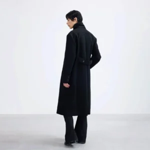 Black long double-breasted overcoat back side view showing adjustable buckle waist belt and straight longline silhouette