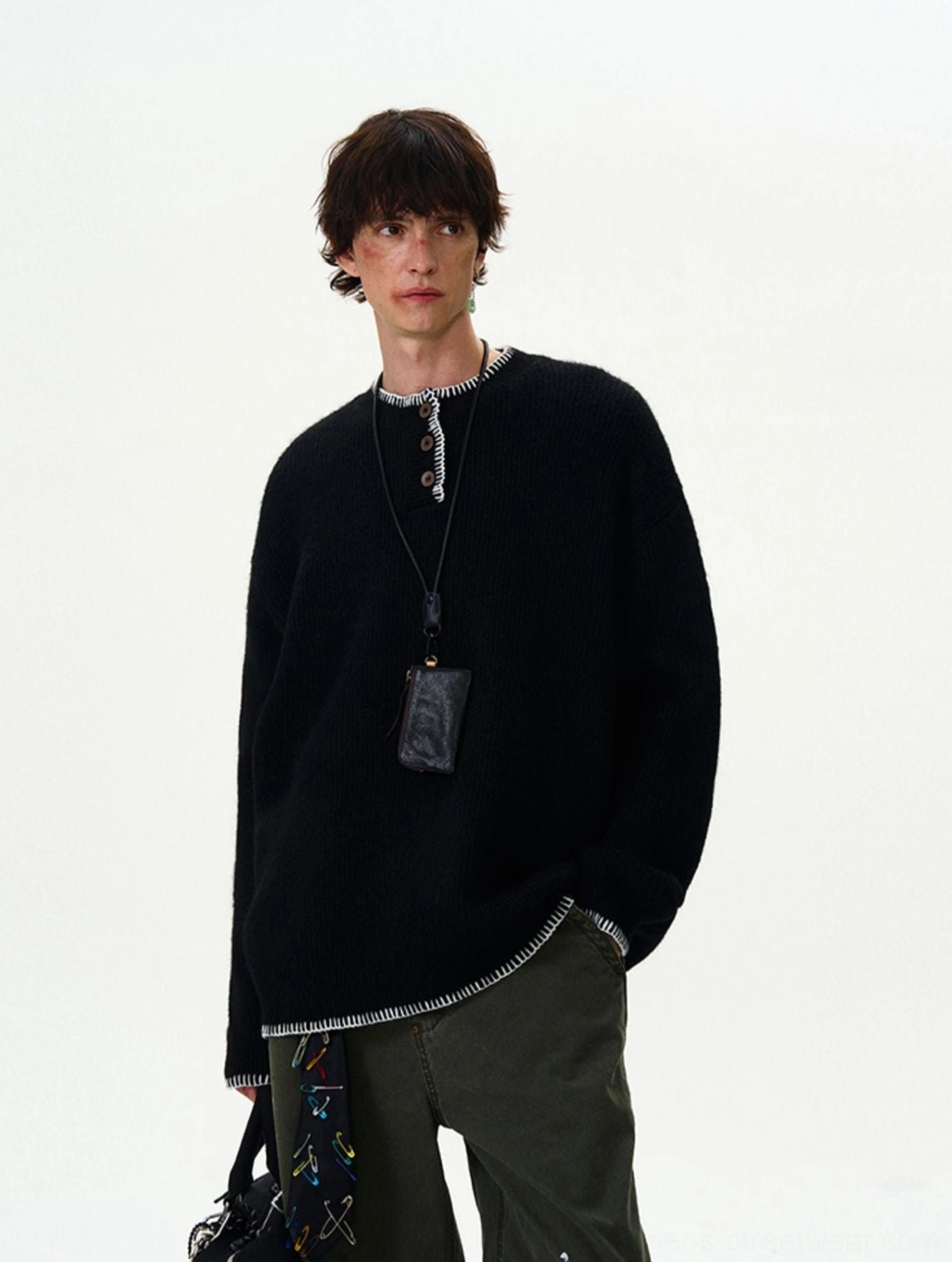 Black loose-fit contrast-stitch knit sweater with white stitched hem and placket styled with a leather crossbody pouch