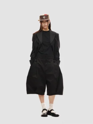 Full-body fashion styling of black loose-fit pleated shorts with black blazer, inner t-shirt, bucket hat, and leather loafers