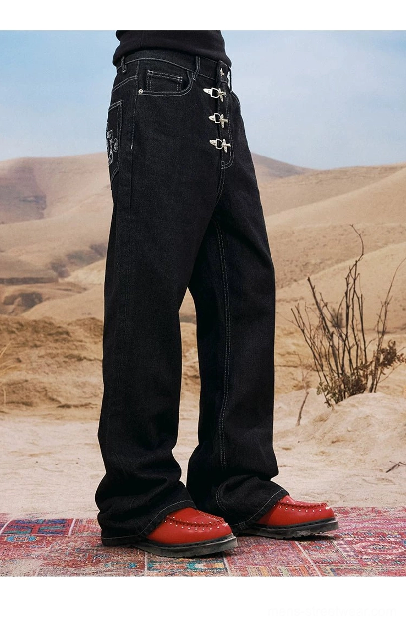 Side view of black low-rise buckle jeans showing contrast stitching, wide leg shape, and embroidered rear pocket detail