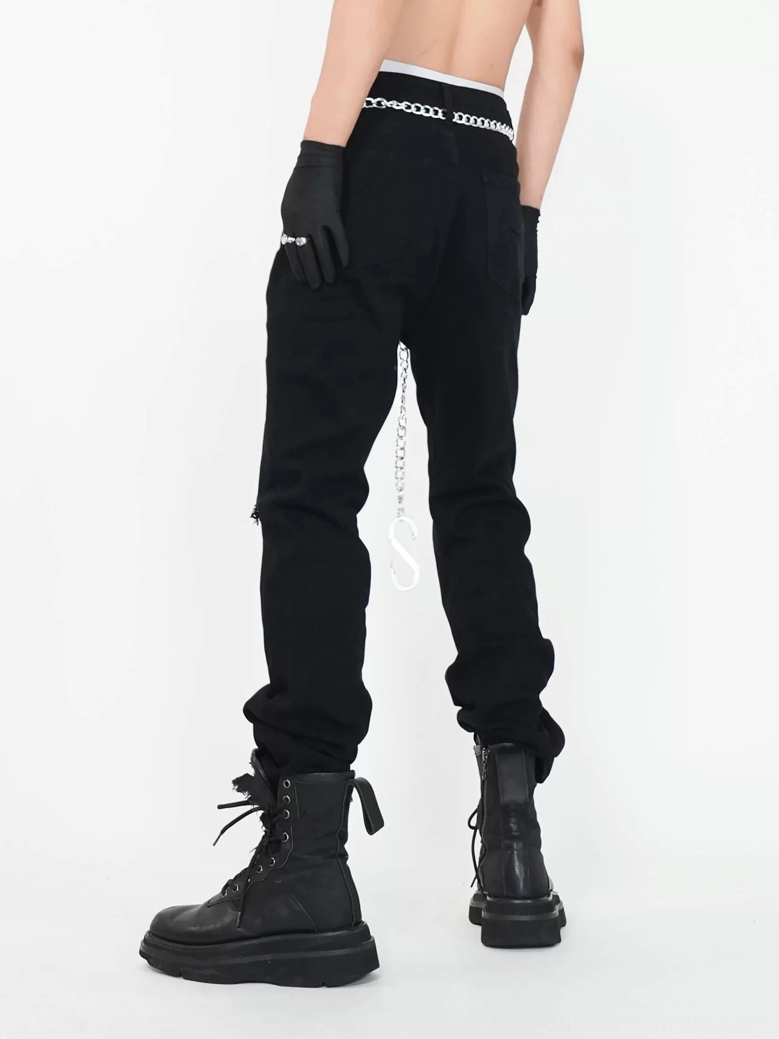 Back view of black low rise ripped punk streetwear jeans showing classic back pockets and silver waist chain detail