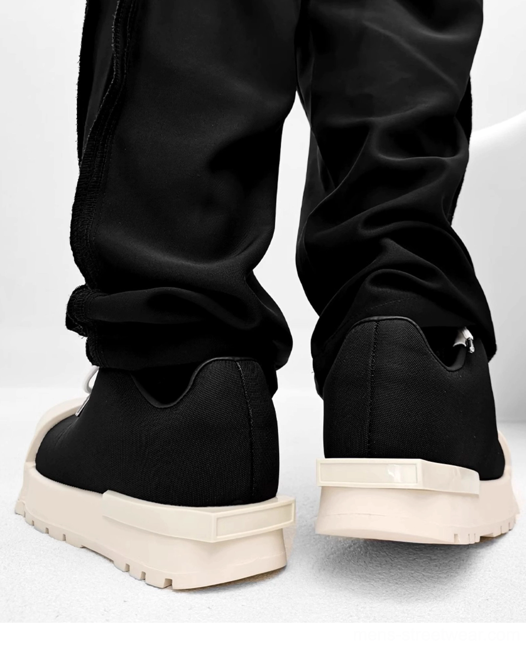 Low-top black platform sneakers with cream rubber sole, rear pull tab, minimalist design, and casual streetwear outfit