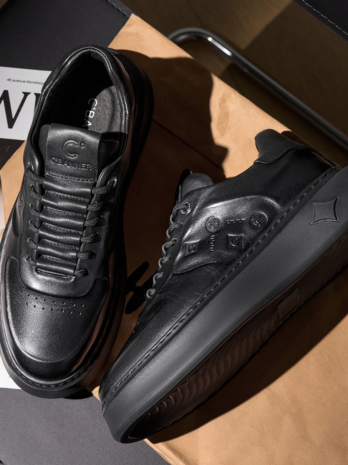 Pair of black low-top platform sneakers with matte synthetic leather, tonal laces, embossed panels, and geometric heel details