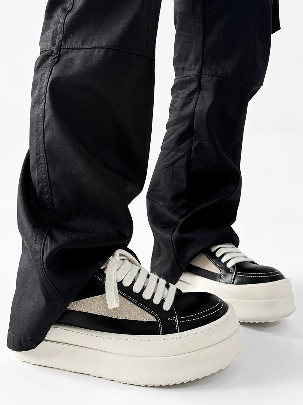 Black low-top platform streetwear sneaker shown from the rear with white laces and thick off-white sole