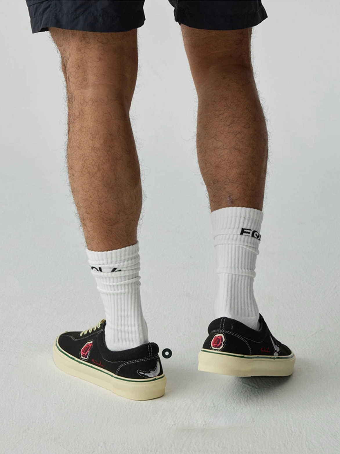 Rear view of black low-top skate shoes showing the heel construction and contrasting off-white rubber outsoles