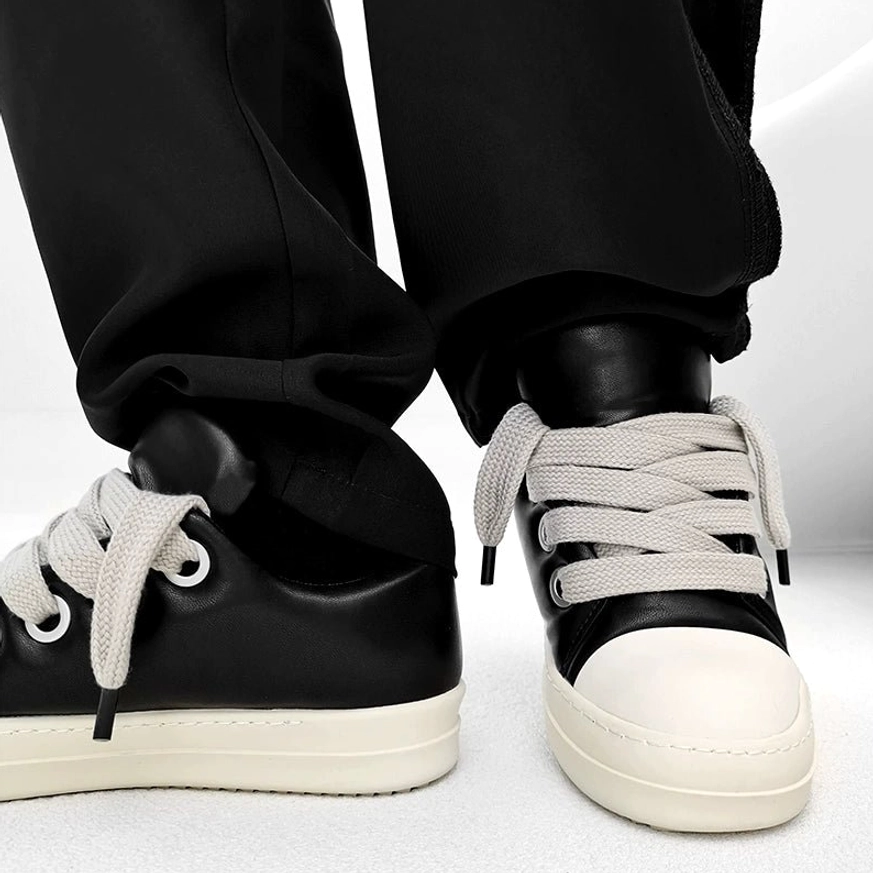 Front and rear view of black low-top thick sole sneakers with polished leather finish, off-white color-blocked toe cap, and modern streetwear styling