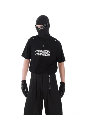 Black short sleeve MANSON streetwear T-shirt with silver chest typography, studded military shoulder tabs, wide-leg trousers, and tactical styling