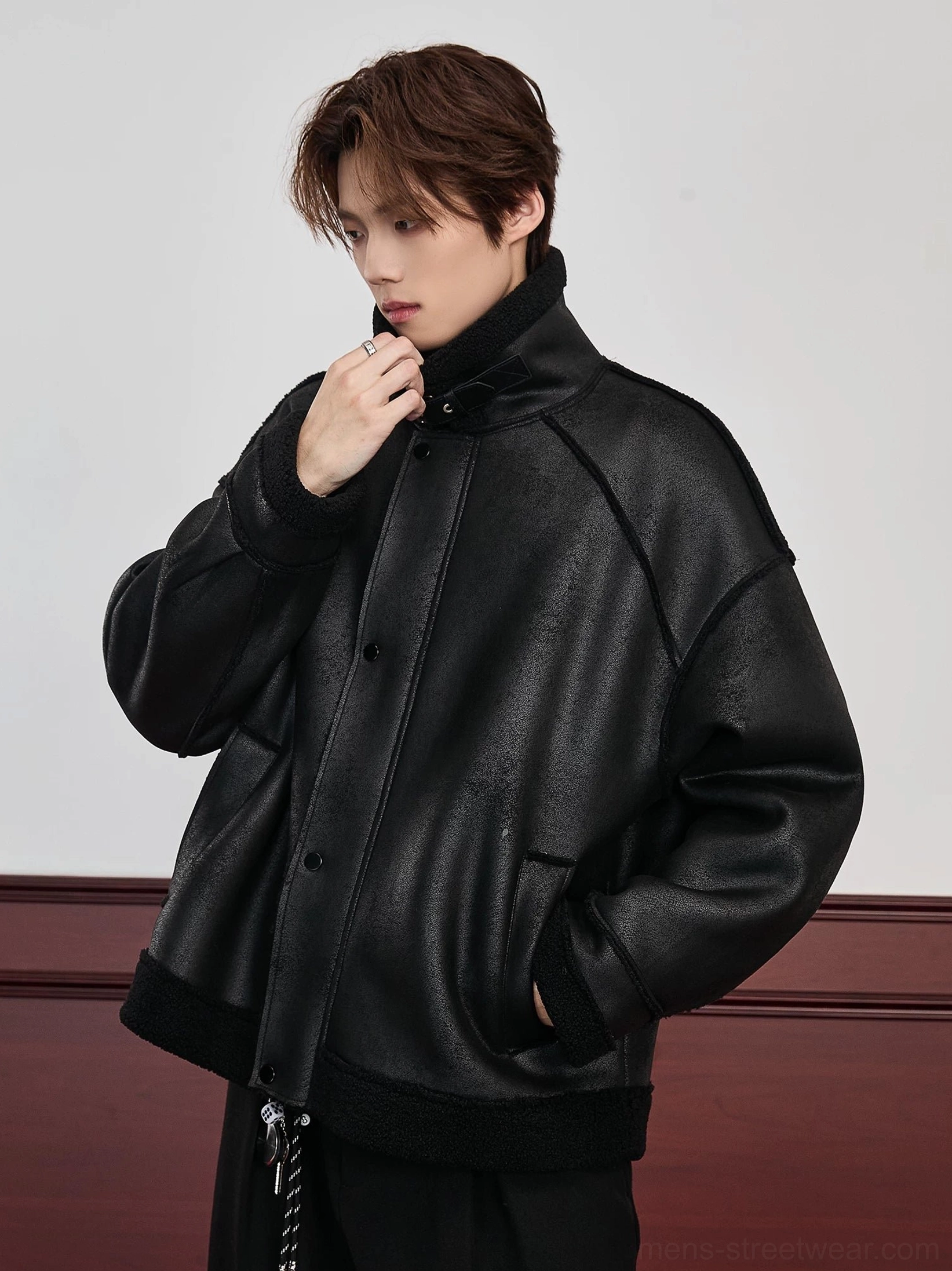 Side three-quarter view of black men's faux shearling aviator jacket with oversized drop shoulder fit, snap button placket, shearling cuff lining, and adjustable drawstring hem