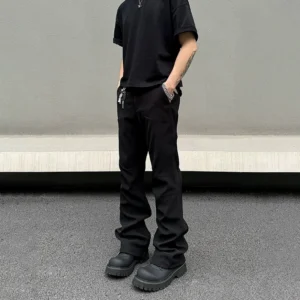 Black men’s flared techwear trousers rear three-quarter view with tailored panel seams, zip hem detail, and metal waist chain