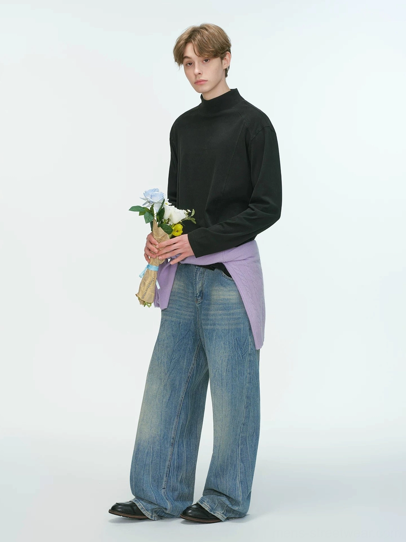 Black men's mock neck long sleeve top shown from the side with a light purple shirt tied around the waist for an avant-garde streetwear look