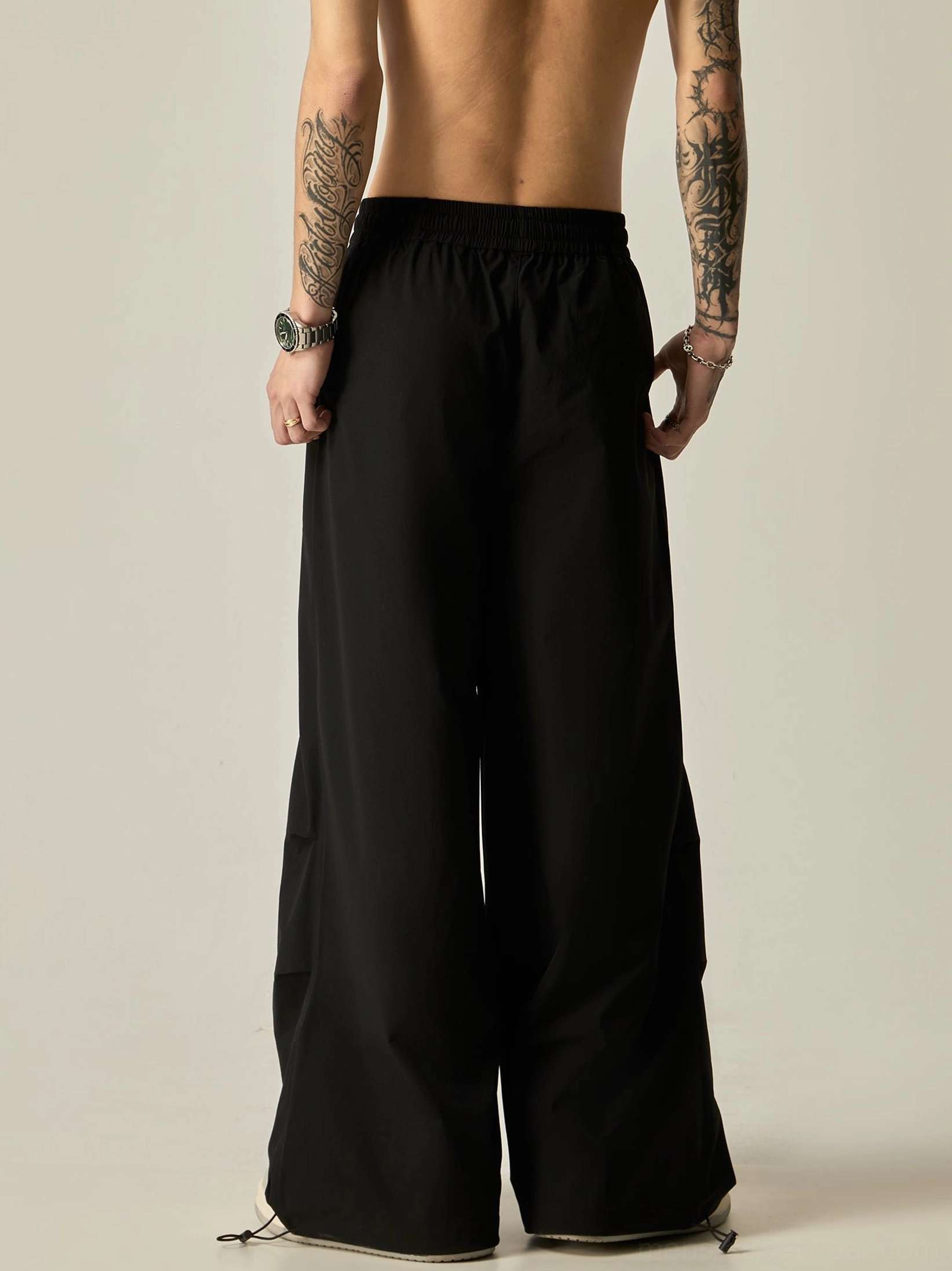 Black men's wide leg streetwear pants shown from the rear with adjustable drawstring cuffs and an oversized relaxed fit
