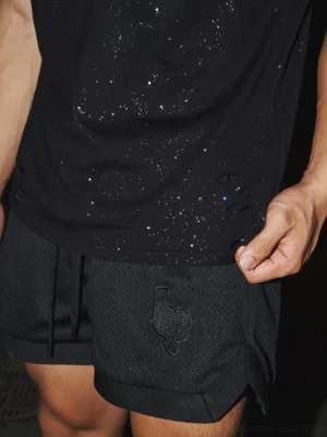 Black mesh embroidered athletic shorts styled with a glitter tank top, showing the breathable sportswear fabric and embroidered front detail
