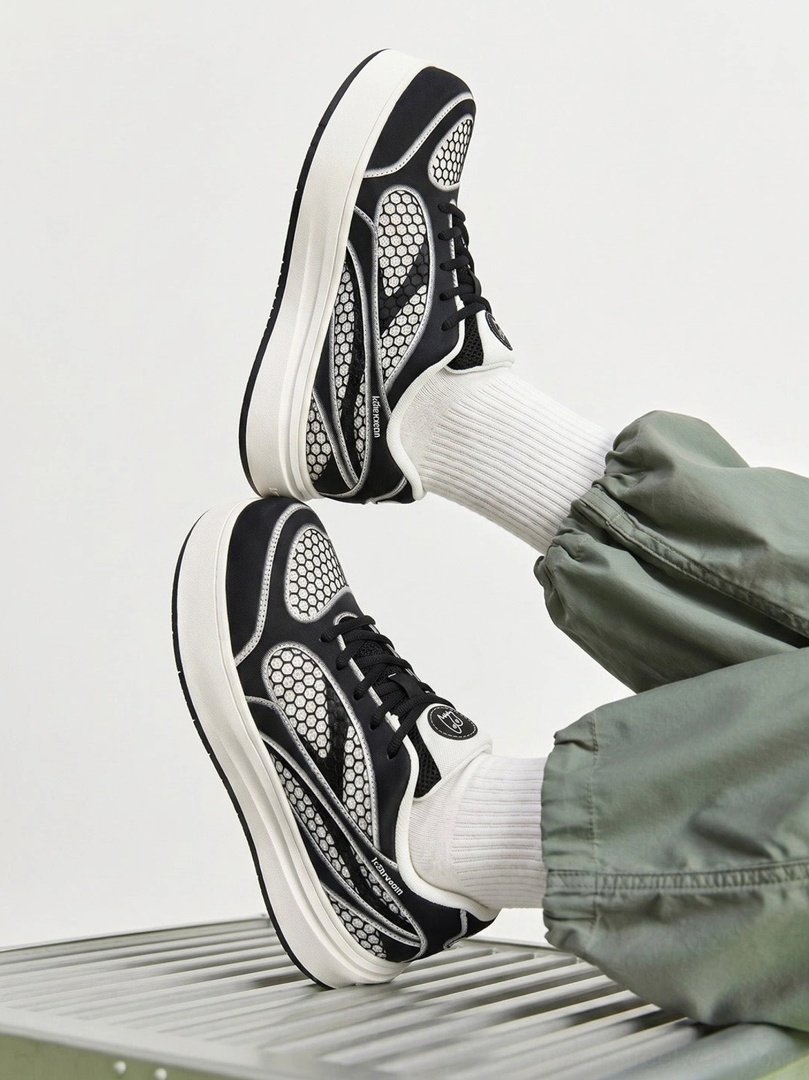 Black mesh panel platform derby sneakers styled with green cargo pants and white socks in a contemporary streetwear look