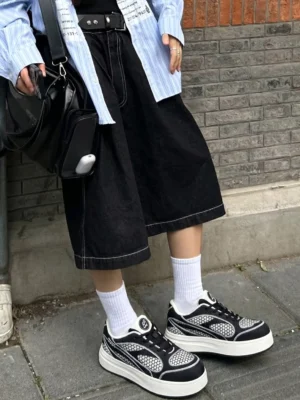 Black mesh platform derby sneakers worn with white crew socks in an urban streetwear outfit beside a brick wall