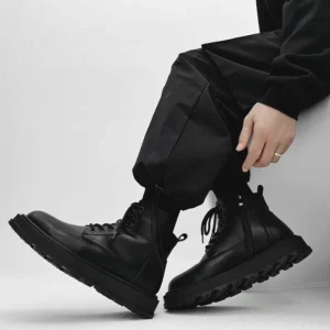 Black mid-top workwear combat boot worn with black cargo pants showing round toe, rugged anti-slip tread outsole, heel pull tab and side profile