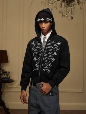 Front half-body view of a black military embroidered zip-up hoodie with symmetrical white cord embroidery, attached hood, and layered Korean streetwear styling