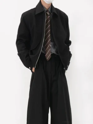 Black minimalist cropped blouson jacket styled with striped shirt tie and wide-leg trousers front full body view