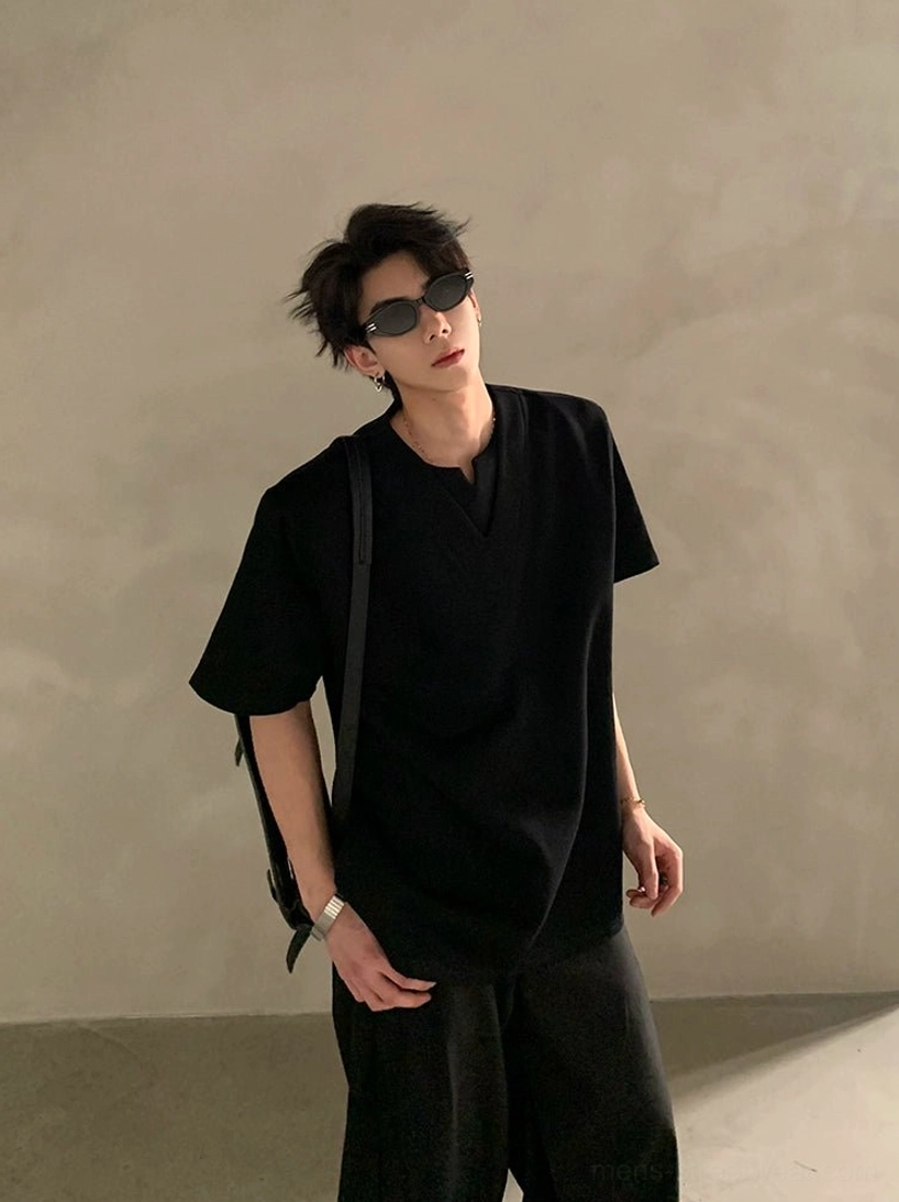 Black minimalist deep V neckline streetwear shirt shown in a front standing outfit with shoulder bag