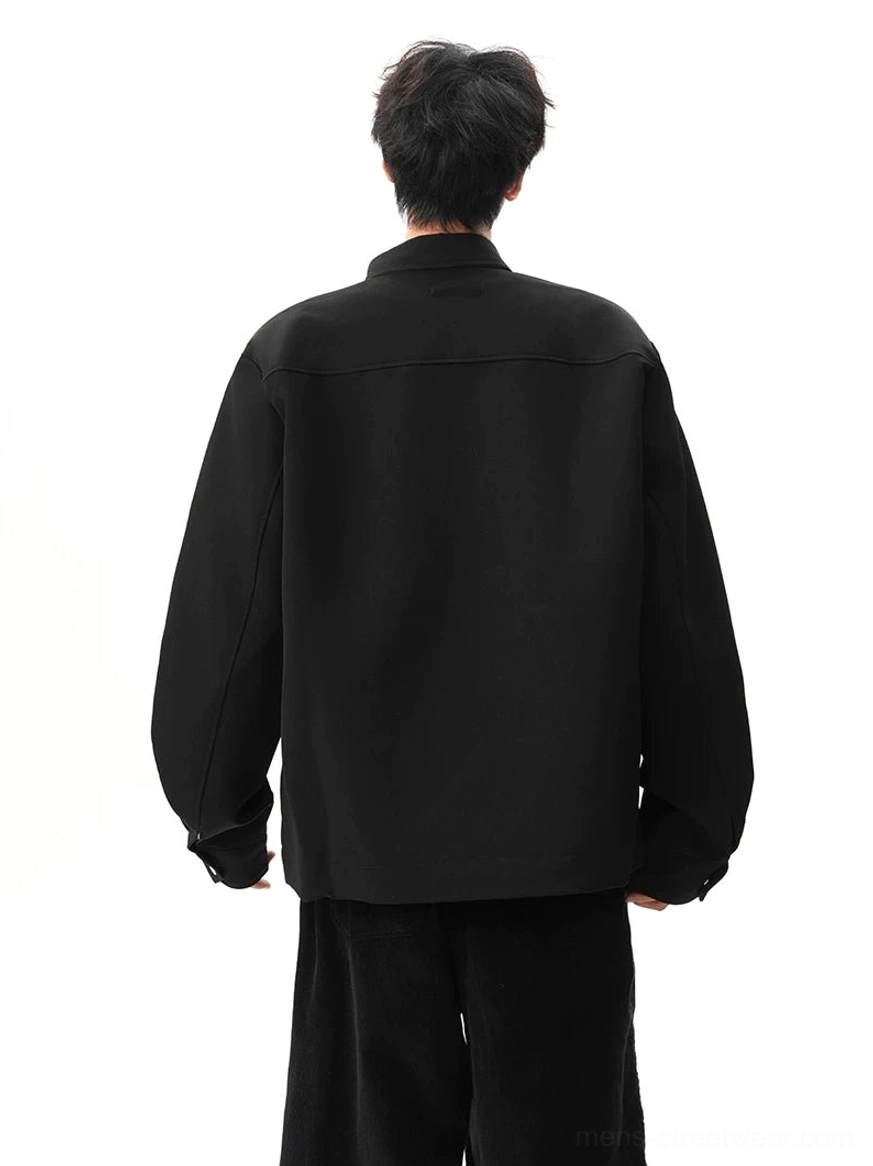 Back view of black minimalist stand collar zip jacket showing clean rear panel center seam and cuff construction