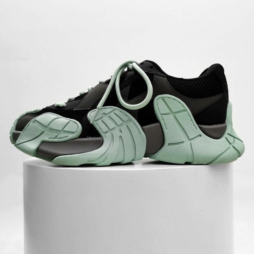 Black futuristic chunky sneaker with mint green outsole accents displayed in a minimalist studio, rugged platform sole and layered upper