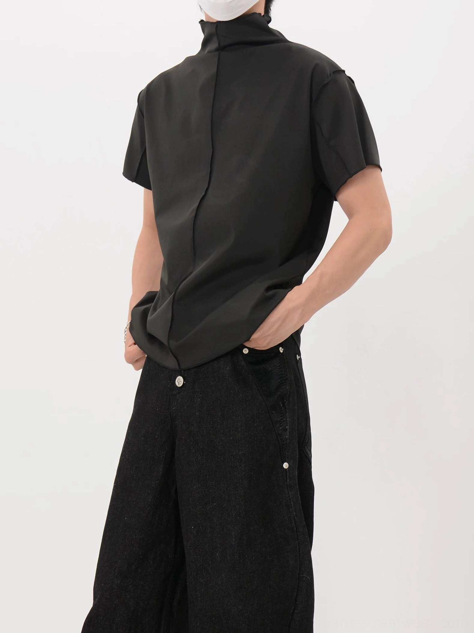 Three-quarter rear view of a black mock neck streetwear shirt showing the curved hem and center back seam